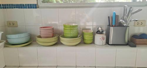 a shelf with a stack of plates and bowls at บ้านพิม in Pran Buri