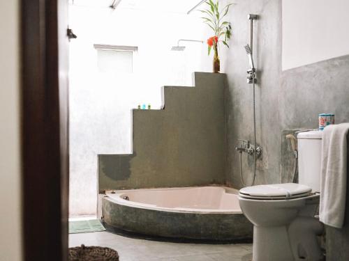 a bathroom with a toilet and a bath tub at The Other Corner Habarana in Habarana