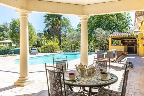 un patio avec une table et des chaises à côté d'une piscine dans l'établissement Villa provençale sur Vence avec Piscine privée, à Vence