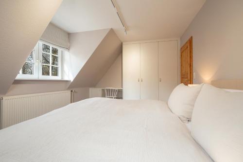 a bedroom with a large white bed and a window at Gut Oehe in Maasholm