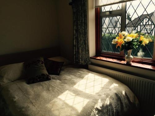 a bedroom with a bed and a vase of flowers in a window at Edgware B&B in Barnet