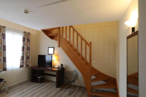 a room with a staircase with a desk and a television at Hôtel de l'Abbaye des Prémontrés in Pont-à-Mousson