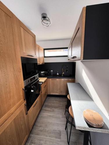 une petite cuisine avec des placards en bois et une table dans l'établissement Résidence Terrasse De Risoul - Magnifique chalet de standing neuf avec vue panoramique au départ du téléski MAE-4951, à Risoul