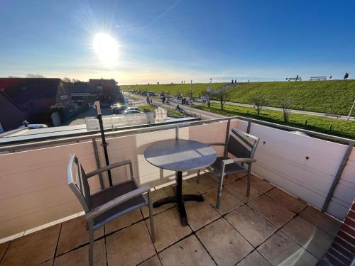 a table and chairs on a balcony with a view of a road at Katrin in Norddeich