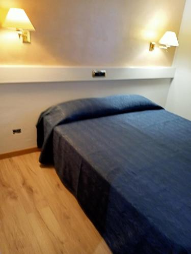a bed in a room with two lights on the wall at Eurohotel in Piacenza