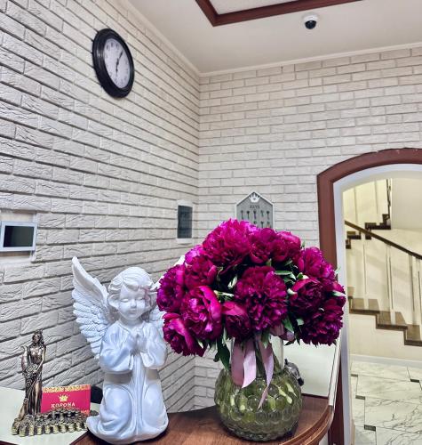 a vase with pink flowers and a statue of an angel at Hotel Korona in Kropyvnytskyi