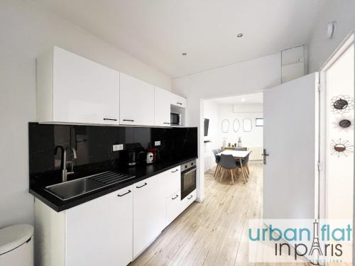 - une cuisine avec des placards blancs, un évier et une table dans l'établissement Urban Flat 181 - Pretty Flat in Levallois, à Levallois-Perret
