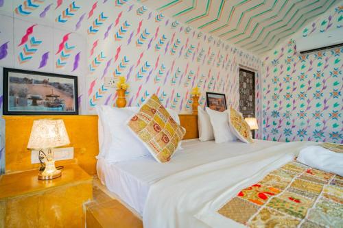 a bedroom with two beds and a wall covered in colorful wallpaper at Khamma Ghani Resort with pool Luxury camp in Jaisalmer in Jaisalmer