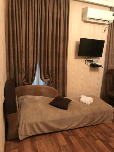 a bedroom with a bed and a television and curtains at Apartment Barita in Tbilisi City