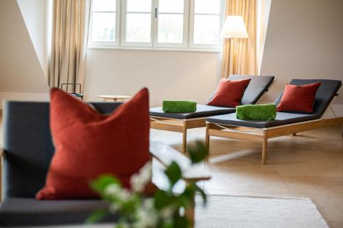 a living room with two couches with red and green pillows at Hotel Stiegl-Gut Wildshut in Wildshut