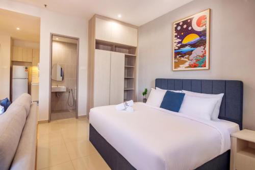 a bedroom with a large white bed and a kitchen at Iconic Regency by Stellar ALV in Bayan Lepas