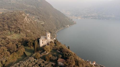 a castle on a hill next to a body of water at La Foresta Monteisola in Monte Isola