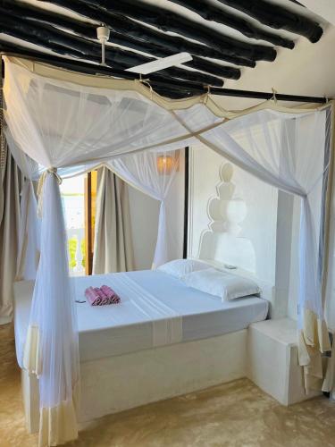 a bedroom with a white bed with a canopy at Stopover Guest House and Restaurant in Lamu