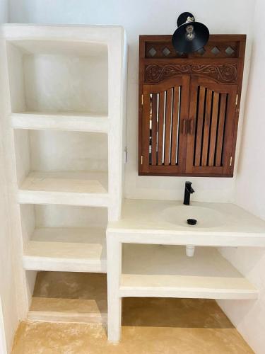 a bathroom with white shelves and a sink at Stopover Guest House and Restaurant in Lamu