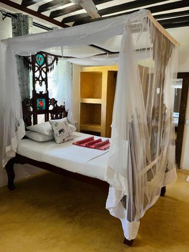 a bedroom with a canopy bed with mosquito nets at Stopover Guest House and Restaurant in Lamu