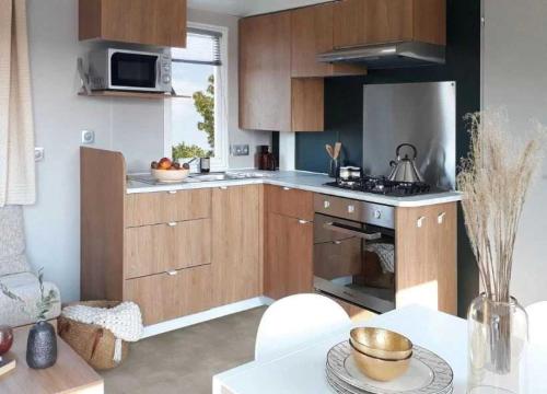 une cuisine avec des armoires en bois et un four à plaques de cuisson dans l'établissement Camping - Parc aquatique - ccahfd0, à Portiragnes