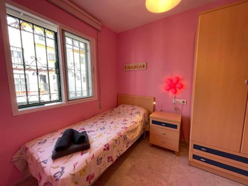 a bedroom with pink walls and a bed with a black chair at Terrasol Chalet en Torre Del Mar in Torre del Mar