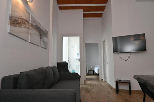 a living room with a couch and a television on a wall at Homenfun Dalt Badalona in Badalona