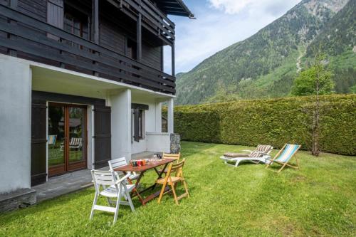 d'une terrasse avec des chaises et une table sur la pelouse. dans l'établissement Cozy big Chalet with Spectacular Mont-Blanc View, à Chamonix-Mont-Blanc