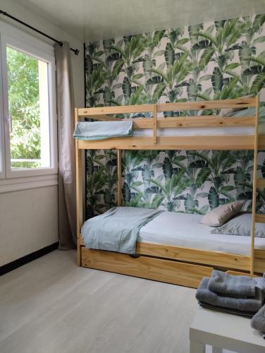 une chambre avec des lits superposés avec un papier peint tropical dans l'établissement Maison carrée - domaine du vieux tilleul, à Meyrueis