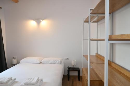 a bedroom with a white bed and a ladder at Homenfun Dalt Badalona in Badalona