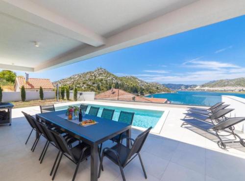 a patio with a table and chairs and a swimming pool at Luxury Villa Navis in Rogotin