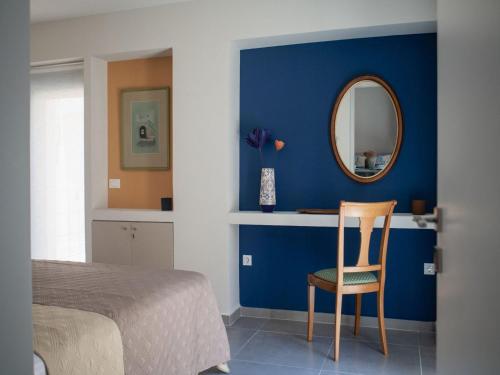 a bedroom with a blue wall with a mirror and a chair at Elegant City Apartment - 250m from Solomos Square in Zakynthos Town
