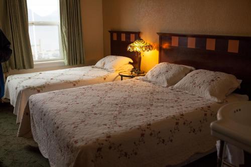 a bedroom with two beds and a lamp and a window at Gilmore Hotel, Trademark Collection by Wyndham in Ketchikan