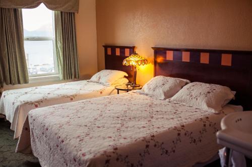 a bedroom with two beds and a lamp and a window at Gilmore Hotel, Trademark Collection by Wyndham in Ketchikan