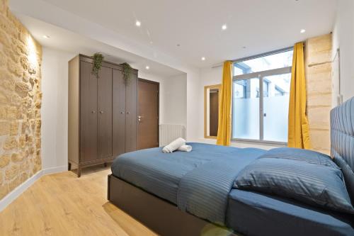 une chambre avec un lit bleu et une grande fenêtre dans l'établissement Splendid Apartment Quartier Palais Royal Free Netflix, à Paris