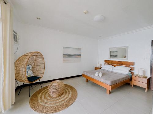 a bedroom with a bed and a chair at Wuthering Heights Bed & Breakfast by the Sea in Dumaguete