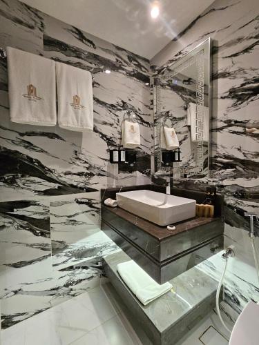 a bathroom with a sink and a marble wall at Royal Plaza Hotel in Duqm