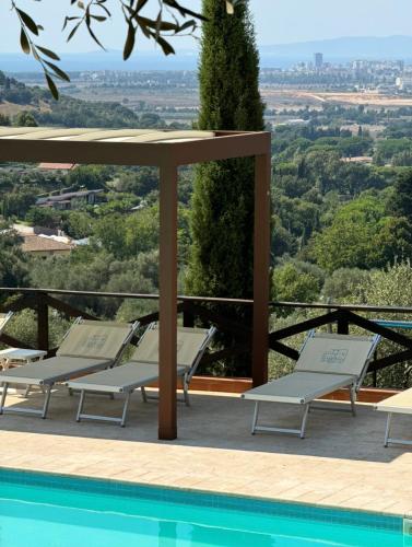 a pool with lounge chairs and a view of the city at Madonna del Poggio B&B in Scarlino