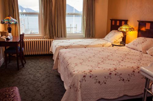 a hotel room with two beds and a desk and windows at Gilmore Hotel, Trademark Collection by Wyndham in Ketchikan