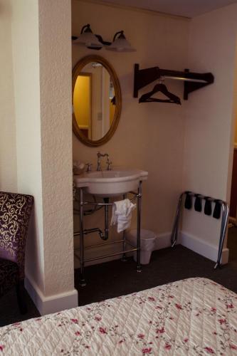 a bathroom with a sink and a mirror and a bed at Gilmore Hotel, Trademark Collection by Wyndham in Ketchikan