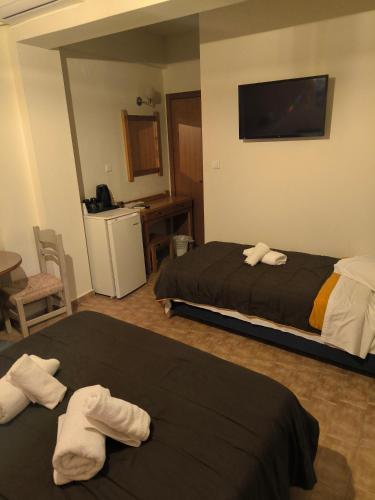 a hotel room with two beds and a flat screen tv at Hotel Almira in Agia Triada