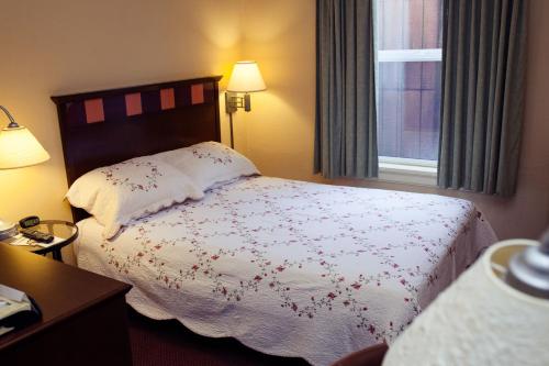 a bedroom with a bed with a white comforter and a window at Gilmore Hotel, Trademark Collection by Wyndham in Ketchikan