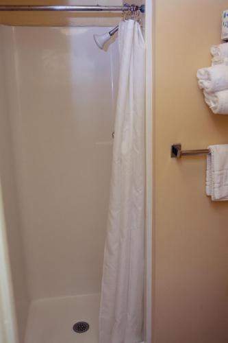 a shower with a white shower curtain in a bathroom at Gilmore Hotel, Trademark Collection by Wyndham in Ketchikan