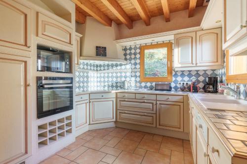 une cuisine avec des armoires blanches et un sol carrelé dans l'établissement Chalet La Rayée - Vue lac et montagne 14p, à Gérardmer