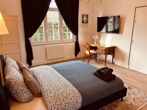 - une chambre avec un lit, un bureau et une télévision dans l'établissement L'Appartement, à Étretat