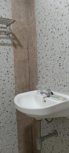 a white sink in a bathroom with a wall at Rezka Roomz Syari'ah in Ende