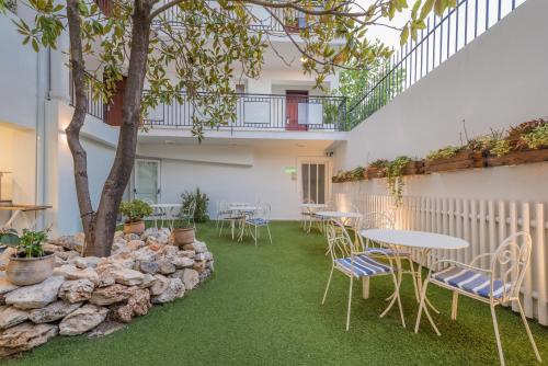 a patio with tables and chairs and a tree at Zante Park Resort & Spa BW Premier Collection in Laganas