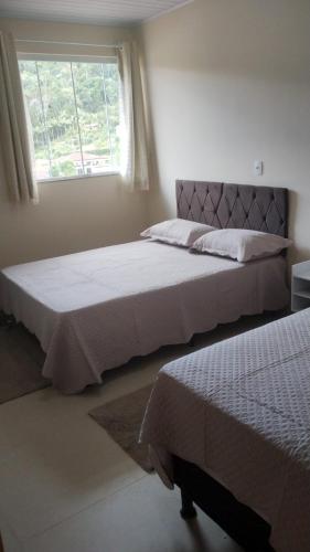 two beds in a bedroom with a window at Casa Vista da Pedra in Domingos Martins