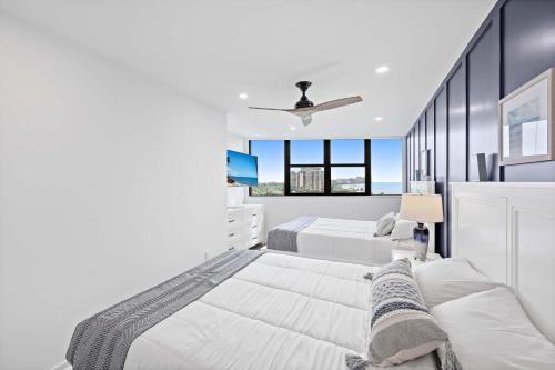 a white bedroom with two beds and a window at Beachfront condo with views of beach and spacious pool in Marco Island