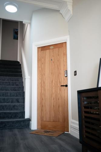 a wooden door in a hallway with stairs at Stunning 2 Bedroom Ground Floor Sea View Apartment in Llandrillo-yn-Rhôs