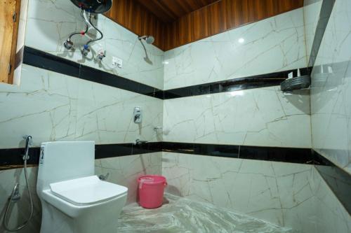 a bathroom with a toilet and a pink trash can at Mellow- A Himalayan Home in Haripūr