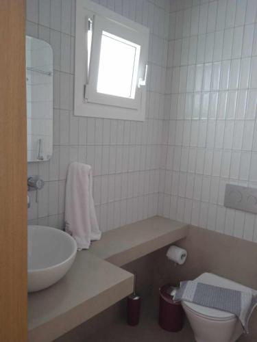 a bathroom with a sink and a toilet and a window at Avra Studios in Myrties