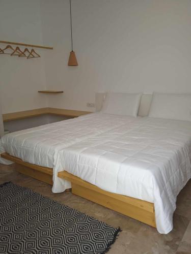 a bedroom with a white bed with a wooden frame at Avra Studios in Myrties