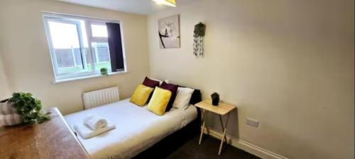 a bedroom with a bed with yellow pillows and a window at Arnstone Spacious 6 bedroom home with parking in Hythe