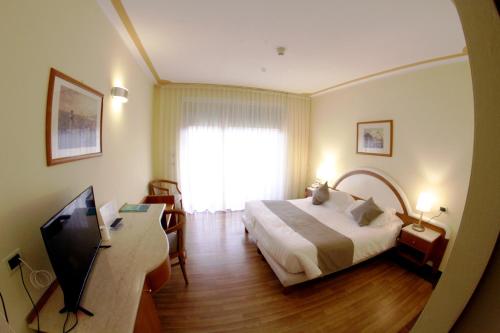 a hotel room with a bed and a television at La Fonte Hotel in Ome